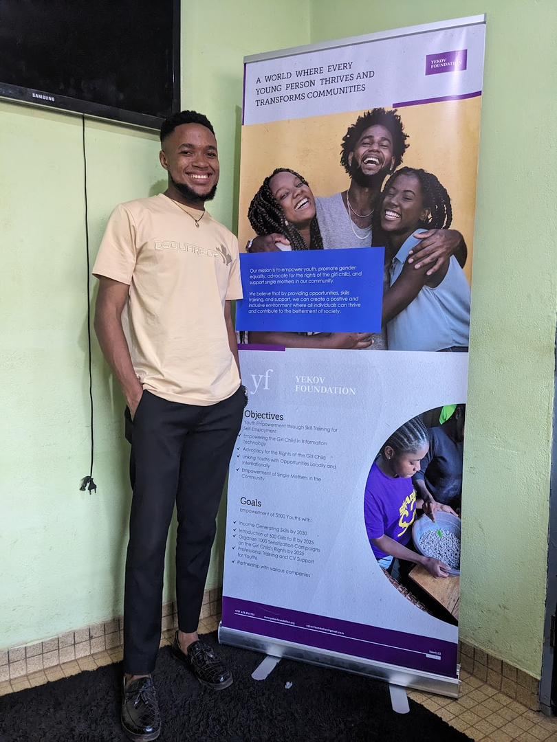 Nsom Emmanuel, IT supervisor at Skye8, beside the Yekov Foundation banner